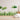 Hand-painted style grass wall decals in various shades of green, arranged against a soft blush pink background. The image features layered blades of grass and a few round leafy shapes, designed to mimic natural foliage with a watercolor texture.